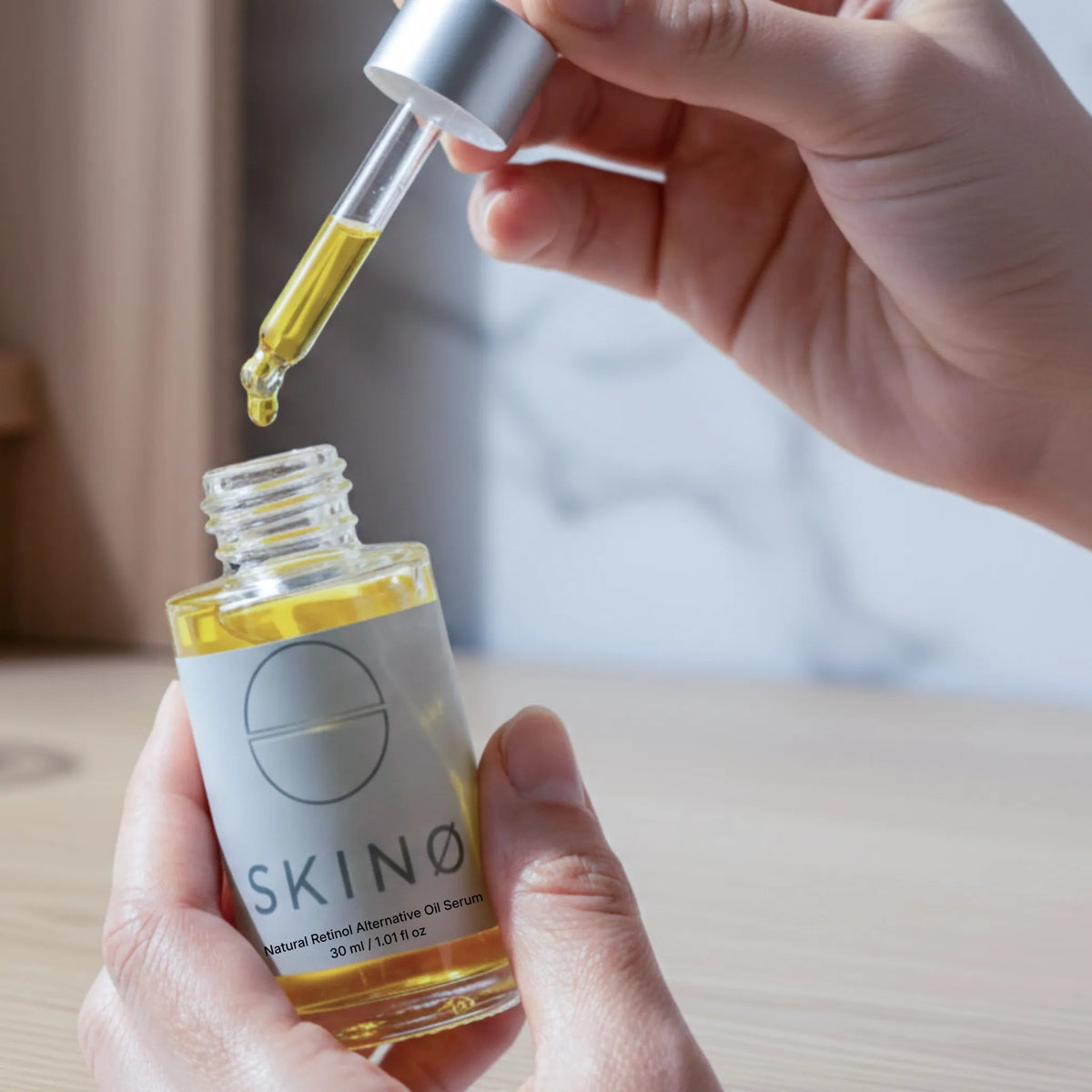 Hand med pipett och gul ansiktsolja – SKINØ Natural Retinol Alternative Oil Serum med bakuchiol och nyponolja