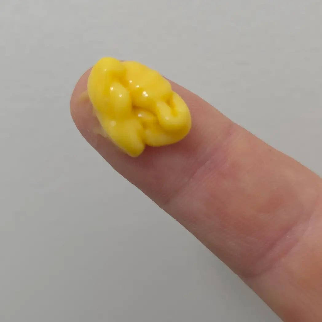 Droppe SKINØ Nordic Glow Vitamin C-serum på fingertopp – gul, krämig textur